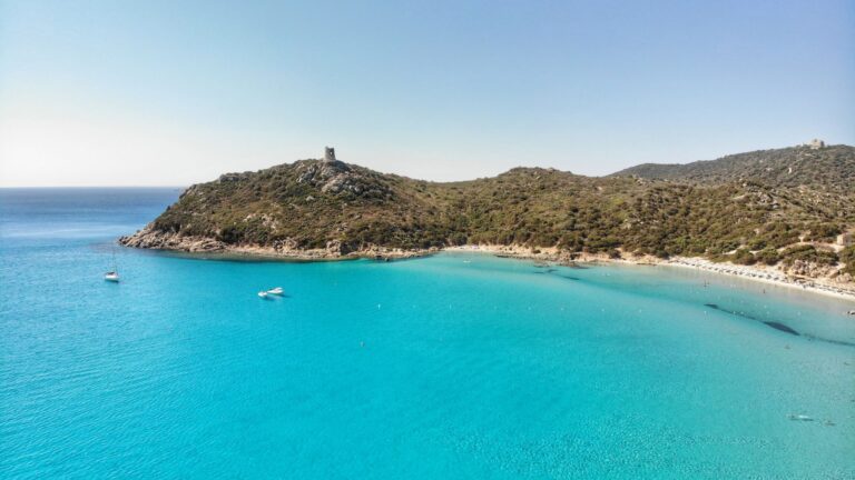 Vista aérea da torre de Porto Giunco e do mar turquesa, na Sardenha