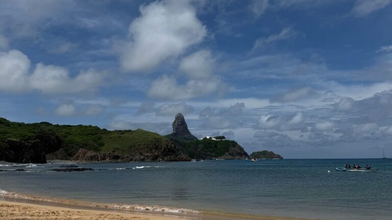 Praia de areia clara com morros verdes ao fundo