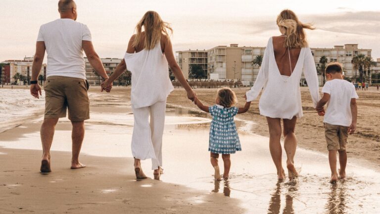 Família caminhando de mãos dadas na praia ao pôr do sol